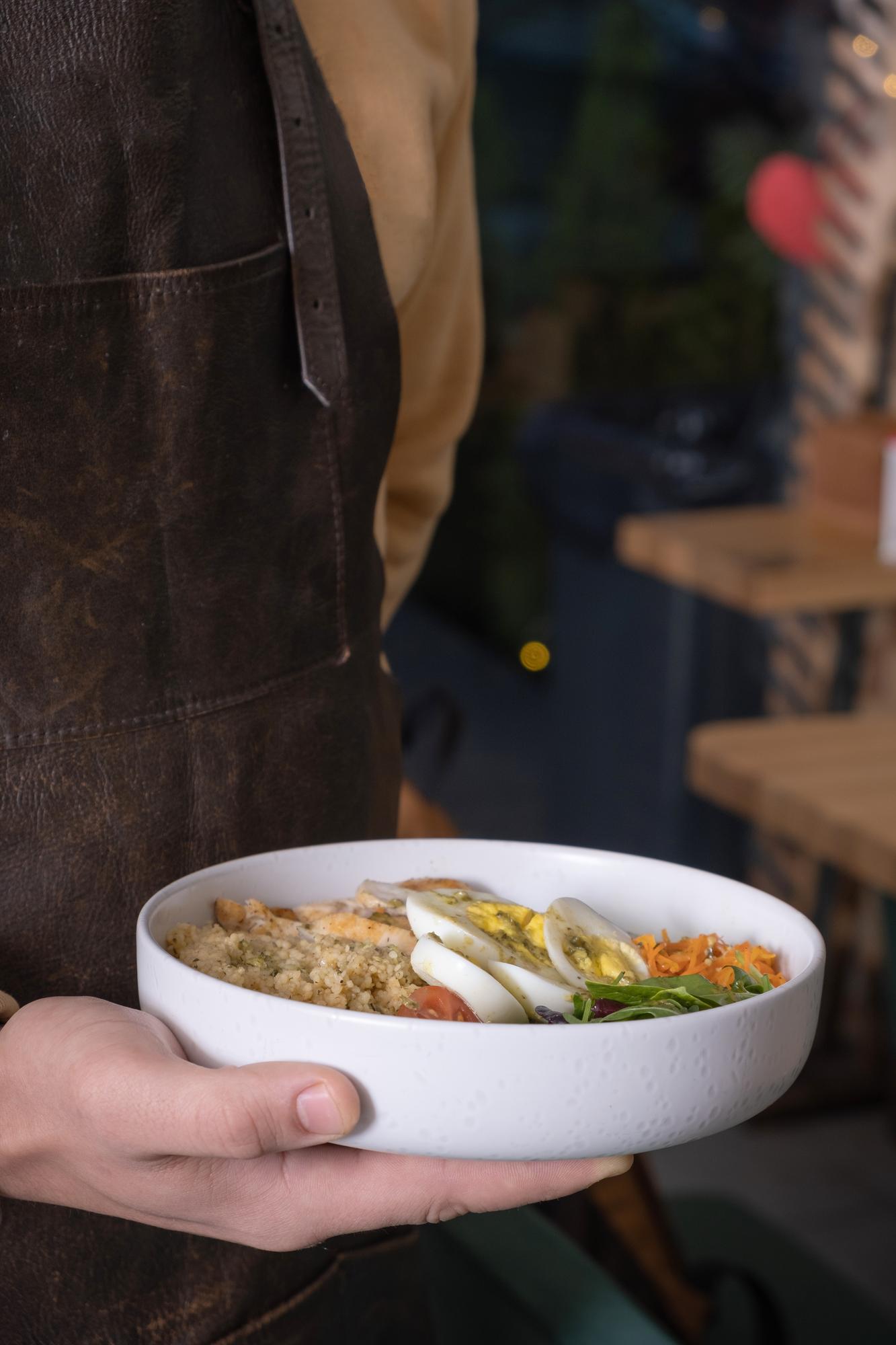 Chef holding rustic bowl with fresh prepared meal